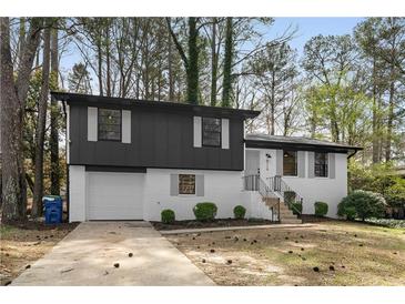 Charming two-story home with black and white painted brick, attached garage, and landscaped yard at 6710 Hidden Brook Trl, Atlanta, GA 30349