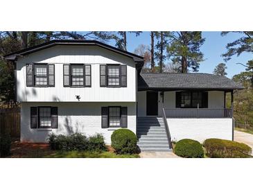 Inviting two-story home featuring a painted brick base, black shutters, and a charming covered front porch at 4087 Signal Rdg, Lilburn, GA 30047
