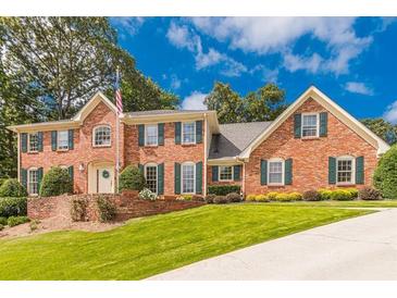 Beautiful brick home featuring a lush front yard and a symmetrical design with vibrant green shutters at 5581 Stapleton Dr, Dunwoody, GA 30338