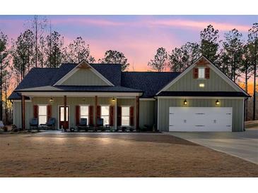 Charming single-story home featuring a covered porch, a two-car garage, and manicured lawn at dusk at 598 Barnwood Dr, Rockmart, GA 30153