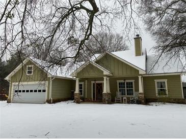 Charming home exterior with a well-manicured lawn and covered porch, complete with an attached garage at 10390 Rivertown Rd, Chattahoochee Hills, GA 30213