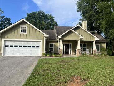 Charming one-story home featuring green siding, stone accents, and a well-manicured front lawn at 10390 Rivertown Rd, Fairburn, GA 30213
