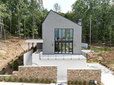 Modern home with gray siding, a stone retaining wall, and an inviting entrance at 1171 Lupo Loop, Chattahoochee Hills, GA 30268