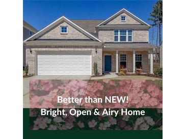 Charming two-story brick home featuring a welcoming front porch, two-car garage, and professionally landscaped yard at 1236 Maston Rd, Auburn, GA 30011