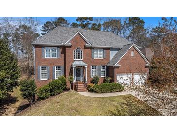 Beautiful two-story brick home with a manicured lawn, gray shutters, and a two-car garage at 358 Woodbrook Crst, Canton, GA 30114