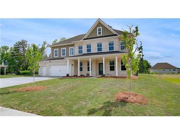 Beautiful two-story home with a well-manicured lawn, attached garage, and classic architectural details at 165 Haverling Pass, Hampton, GA 30228