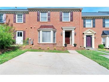 Charming brick townhome featuring a bay window, manicured lawn, and ample parking space at 315 Towergate Pl, Atlanta, GA 30350