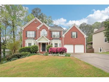 Beautiful two-story brick home with well-manicured lawn, mature trees and attached two-car garage at 2118 Township Dr, Woodstock, GA 30189