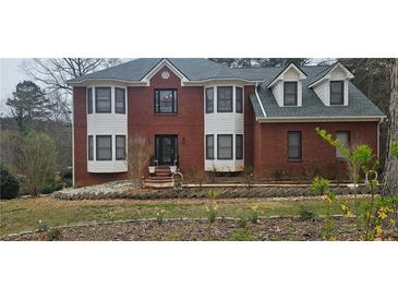 Charming two-story brick home featuring bright white trim and black accents, set against a natural landscape at 3715 Millers Pond Way, Snellville, GA 30039