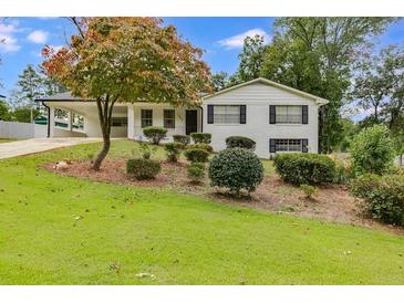 Charming home featuring a brick facade, a well-manicured lawn, and a convenient carport at 1083 Amelia Sw Dr, Marietta, GA 30060
