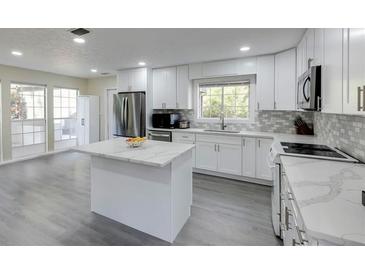 Bright, updated kitchen boasts white cabinets, stainless steel appliances, and gray backsplash at 285 Glen Lake Dr, Sandy Springs, GA 30327