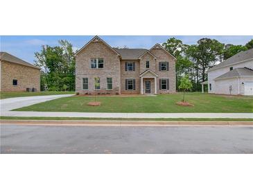 Two-story brick home with a well-manicured lawn and dark shutters on a sunny day at 177 Haverling Pass, Hampton, GA 30228