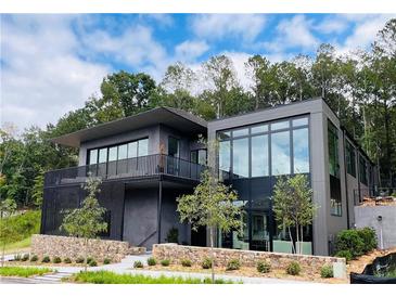 Modern two-story home featuring clean lines, a balcony, walls of windows, and lush landscaping at 1131 Lupo Loop, Chattahoochee Hills, GA 30268