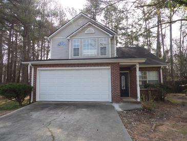 Charming two-story home features a brick facade and a two-car garage, nestled among mature trees at 545 Haymarket Ct, Riverdale, GA 30296