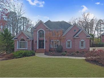 Charming two-story red brick home with a manicured lawn and mature landscaping at 5980 Mallet Ct, Cumming, GA 30040