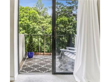 View of a cozy balcony with outdoor seating, patterned rug, and lush green trees in the background at 300 Johnson Ferry Ne Rd # A313, Atlanta, GA 30328