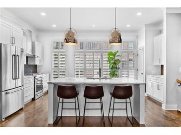 Bright kitchen boasts a center island with seating, stainless steel appliances, and generous natural light from window shutters at 818 Highland Green Ne Way # 818, Atlanta, GA 30306