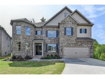 Charming two-story brick home with attached two-car garage, manicured lawn, and tasteful landscaping at 5533 Addison Woods Pl, Buford, GA 30518