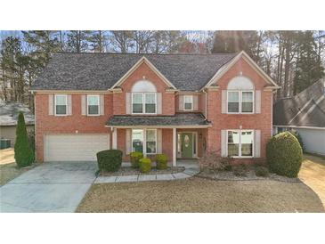 Charming two-story brick home with a well-manicured lawn, attached garage, and inviting front porch at 675 Timber Ives Dr, Dacula, GA 30019