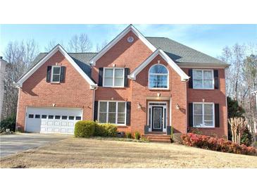 Charming brick two-story home featuring a manicured lawn, attached two car garage and front flower beds at 1023 Hawk Creek Trl, Lawrenceville, GA 30043