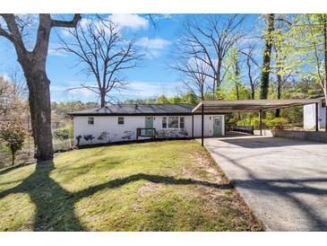 Charming single-story home with white brick, a green door, carport, and well-maintained lawn at 629 Moselle Sw Dr, Mableton, GA 30126