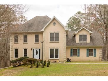 Charming two-story home featuring a welcoming entrance, lush lawn, and mature trees at 5150 Rockford Ln, Stockbridge, GA 30281