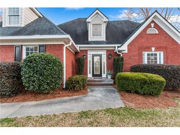 Charming red brick home with a beautifully landscaped front yard and an inviting glass-paneled front door at 816 Ivy Ridge Dr, Loganville, GA 30052