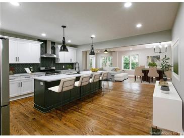 Modern kitchen with white cabinets, black backsplash, large island and stainless steel appliances at 2143 Lyle Ave, College Park, GA 30337