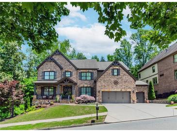 Stunning brick two-story home with a manicured lawn and a three-car garage at 1351 Ashbury Park Dr, Hoschton, GA 30548