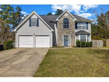 Charming two-story home featuring a two-car garage, stone accents, and manicured front lawn at 6031 Autumn Green Dr, Fairburn, GA 30213