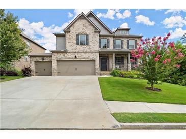 Charming two-story brick home featuring a manicured lawn, three-car garage, and inviting front porch at 4316 Woodland Bank Blvd, Buford, GA 30518