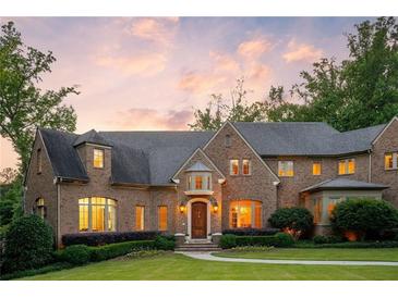 Stunning brick home showcasing manicured lawn, mature landscaping, and a welcoming entrance at dusk at 4520 Garmon Nw Rd, Atlanta, GA 30327