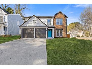 Charming two-story home with a well-manicured lawn, two-car garage, and a bright blue front door at 1074 Wenham Ln, Lawrenceville, GA 30044