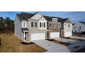 Modern townhomes boast brick and siding exteriors with attached garages and newly landscaped lawns at 167 Belldown Ct, Mcdonough, GA 30253