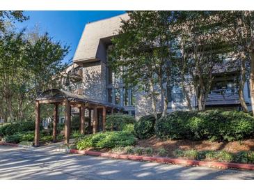 Elegant condo building with stone facade and covered entrance, surrounded by mature trees and landscaping at 1303 Highland Bluff Se Dr # 303, Atlanta, GA 30339