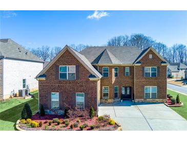 Beautiful brick home with lush landscaping and a well-manicured lawn on a sunny day at 5910 Roxboro Ct, Cumming, GA 30040