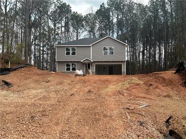 Two-story home with a front-entry two-car garage on a partially cleared lot surrounded by dense trees at 35 Emerald Ln, Covington, GA 30014