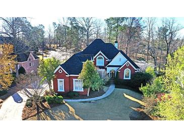 Charming two-story home with landscaped yard and circular driveway nestled among mature trees at 6610 Sunbriar Dr, Cumming, GA 30040