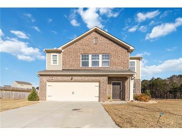 Charming two-story brick home featuring an attached two-car garage and a well-maintained front yard at 891 Feldman Chase, Loganville, GA 30052