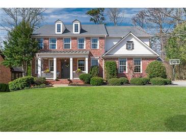 Charming two-story brick home with manicured lawn and inviting front porch, perfect for a Gathering at 4675 Allistair Dr, Cumming, GA 30040