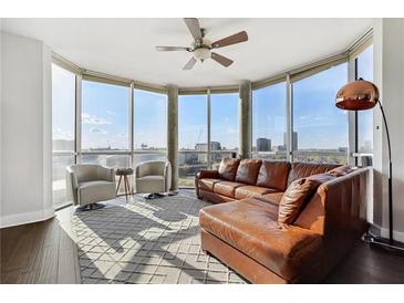 Bright living room with large windows, hardwood floors, and modern furniture and a brown leather sectional sofa at 285 Centennial Olympic Park Nw Dr # 904, Atlanta, GA 30313