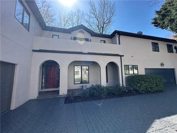 Stucco-clad home with arched entryway, brick driveway, two-car garage, and manicured landscaping at 3491 Roswell Ne Rd # D, Atlanta, GA 30305