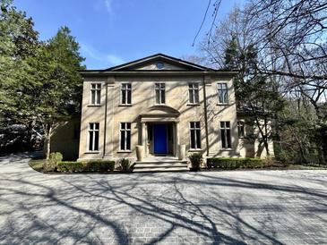 Elegant stone home with a blue front door, manicured landscaping and a circular drive at 973 Peachtree Battle Ave, Atlanta, GA 30327