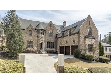 Stunning stone-clad home features a circular driveway, three-car garage, and lush landscaping at 4820 Marina Ln, Mableton, GA 30126