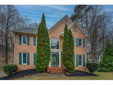 Charming two-story brick home featuring teal shutters, green front door, and manicured landscaping at 2070 Sweetgum Trl, Cumming, GA 30041