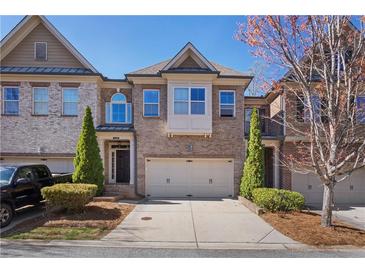 Charming brick townhome featuring an attached two-car garage and beautifully landscaped front yard at 7630 Glisten Ave, Atlanta, GA 30328