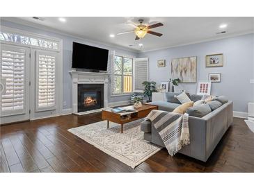 Bright living room boasts a fireplace, ceiling fan, hardwood floors, and light gray walls at 7630 Glisten Ave # 304, Atlanta, GA 30328