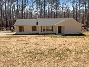 Charming single-story home with a neutral exterior and a well-maintained yard surrounded by a lush tree line at 70 Wall St, Hampton, GA 30228