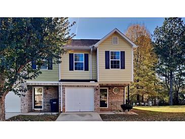 Charming two-story townhome featuring a one-car garage and well-maintained front lawn at 955 Magnolia Gardens Walk, Mcdonough, GA 30253