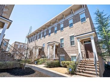 Inviting exterior view of a multi-story brick townhome with well-maintained landscaping and a classic front door at 2119 Dee Dee Muse Nw Ln, Atlanta, GA 30318